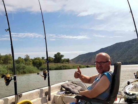 Das Bild zeigt Jürgen im Boot und 3 ausgelegte Angelruten unweit eines Schilfgürtels.