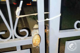 Das Foto zeigt das Tor zum Parkplatz, dass sicher mit einer dünnen Kordel zugebunden ist.